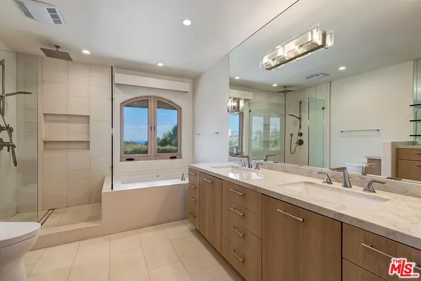 a spacious bathroom with a bathtub shower sink mirror and toilet