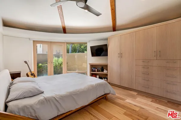 a bedroom with a bed and a flat tv screen on dresser