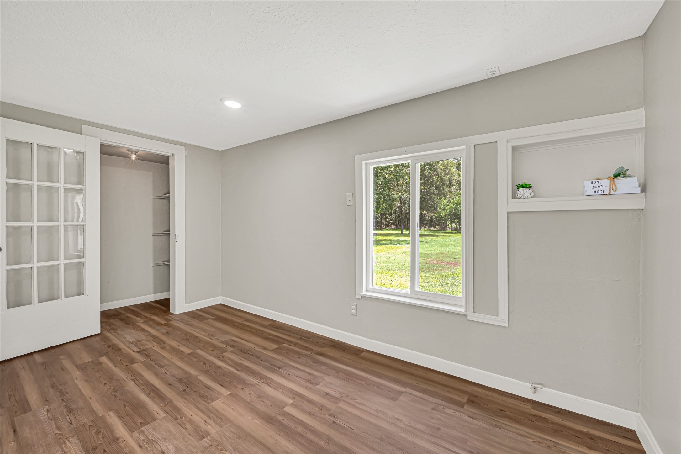 4568 Dunnam Road, Unit B Houston, TX 77345 - Photo 12 of 15 The secondary bedroom is a bright and inviting room offering natural light and scenic backyard views. It has a walk-in closet with glass doors and shelving. This room would also be perfect for a home-office or hobby room.