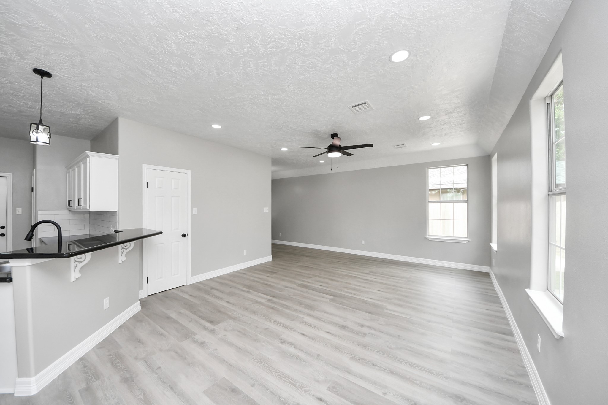 1105 East Kyle Road Clute, TX 77531 - Photo 5 of 44 This spacious, open-concept living area features modern vinyl plank flooring, neutral gray walls, and recessed lighting.