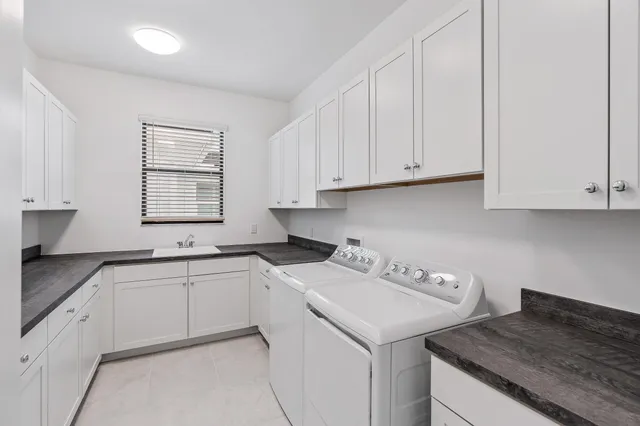 a kitchen with a sink dishwasher and white cabinets with wooden floor