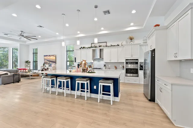 a kitchen with stainless steel appliances kitchen island granite countertop a stove a sink a dining table and chairs with wooden floor