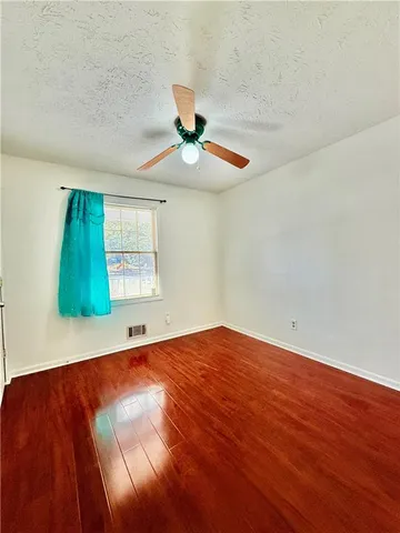 a view of an empty room with window and chandelier fan