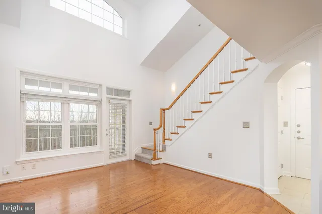 a view of an empty room with wooden floor and windows