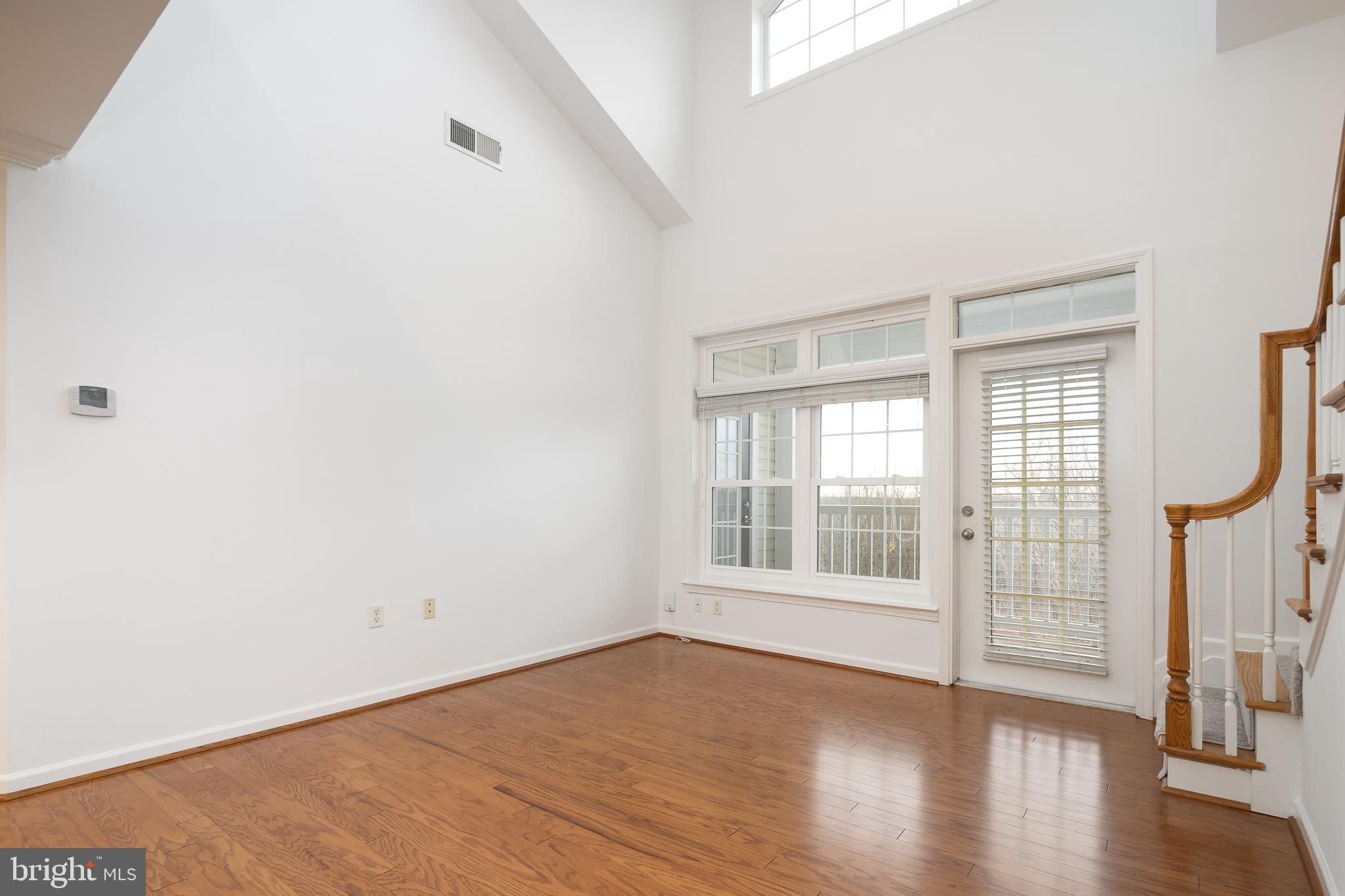 512 Sunset View Terrace Southeast, Unit 402 Leesburg, VA 20175 - Photo 8 of 30 an empty room with wooden floor and windows