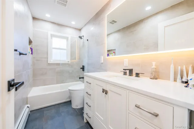a bathroom with a bathtub shower sink vanity mirror and toilet