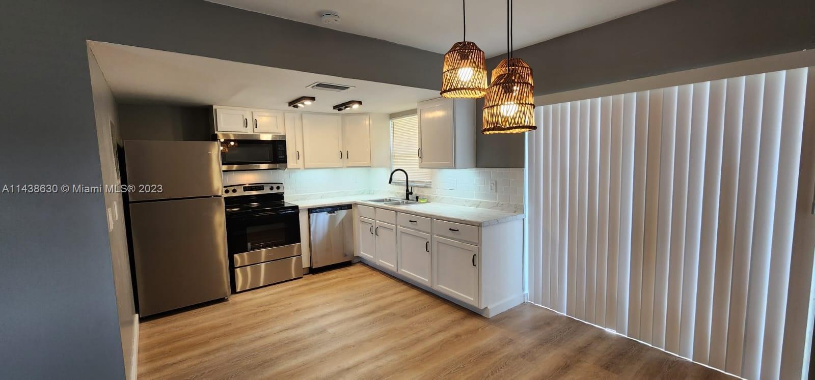 5321 Northwest 27th Street, Unit A4 Lauderhill, FL 33313 - Photo 3 of 19 a kitchen with stainless steel appliances granite countertop a refrigerator a sink dishwasher a stove and white countertops with wooden floor