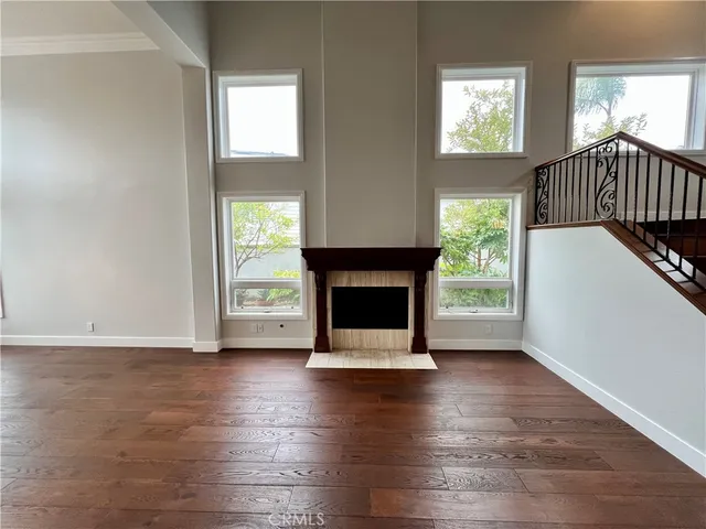 a view of an empty room with wooden floor fireplace and a window