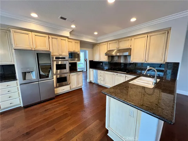 a kitchen with stainless steel appliances wooden cabinets a stove a sink and a refrigerator