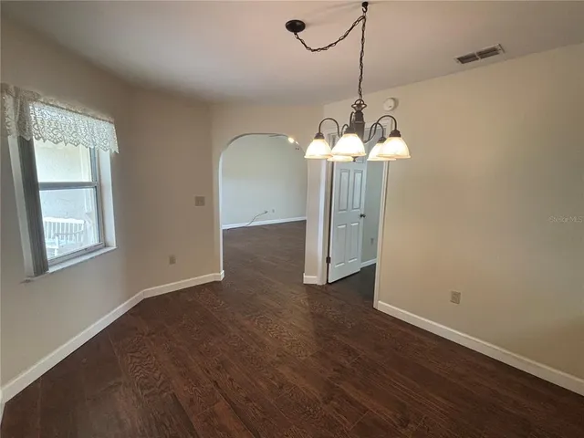a view of a room with wooden floor staircase and a chandelier
