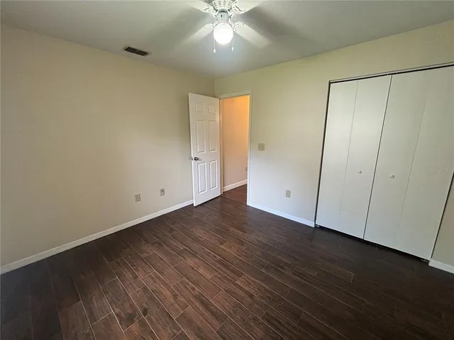 an empty room with wooden floor and fan