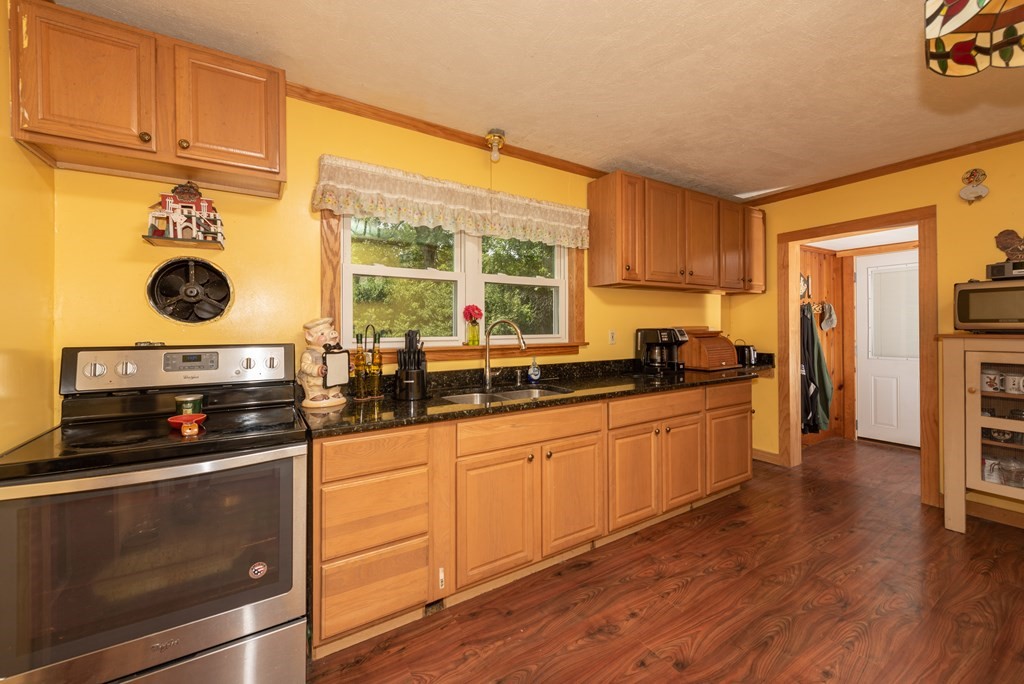 90 Anawan Street Rehoboth, MA 02769 - Photo 6 of 24 a kitchen with stainless steel appliances a stove a sink and white cabinets with wooden floor