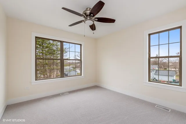 an empty room with windows and ceiling fan
