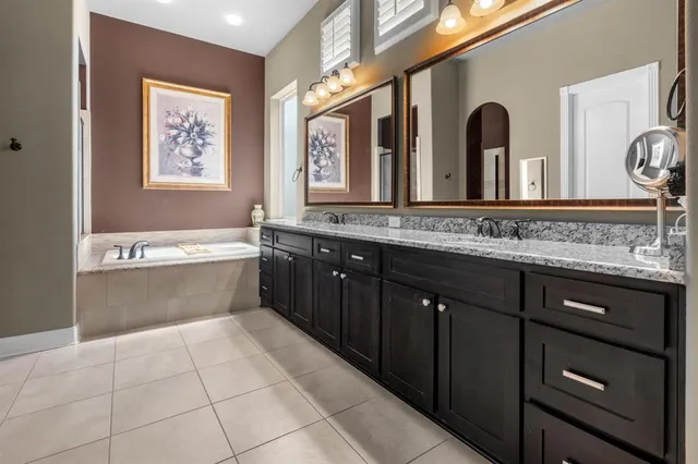 a spacious bathroom with a granite countertop double vanity sink a mirror and bathtub