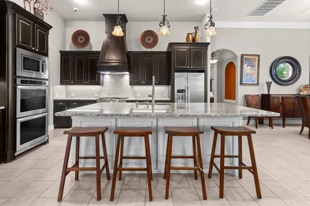 a kitchen with stainless steel appliances granite countertop a kitchen island a dining table and chairs