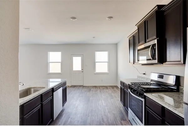 a kitchen with stainless steel appliances granite countertop a stove a sink and a microwave