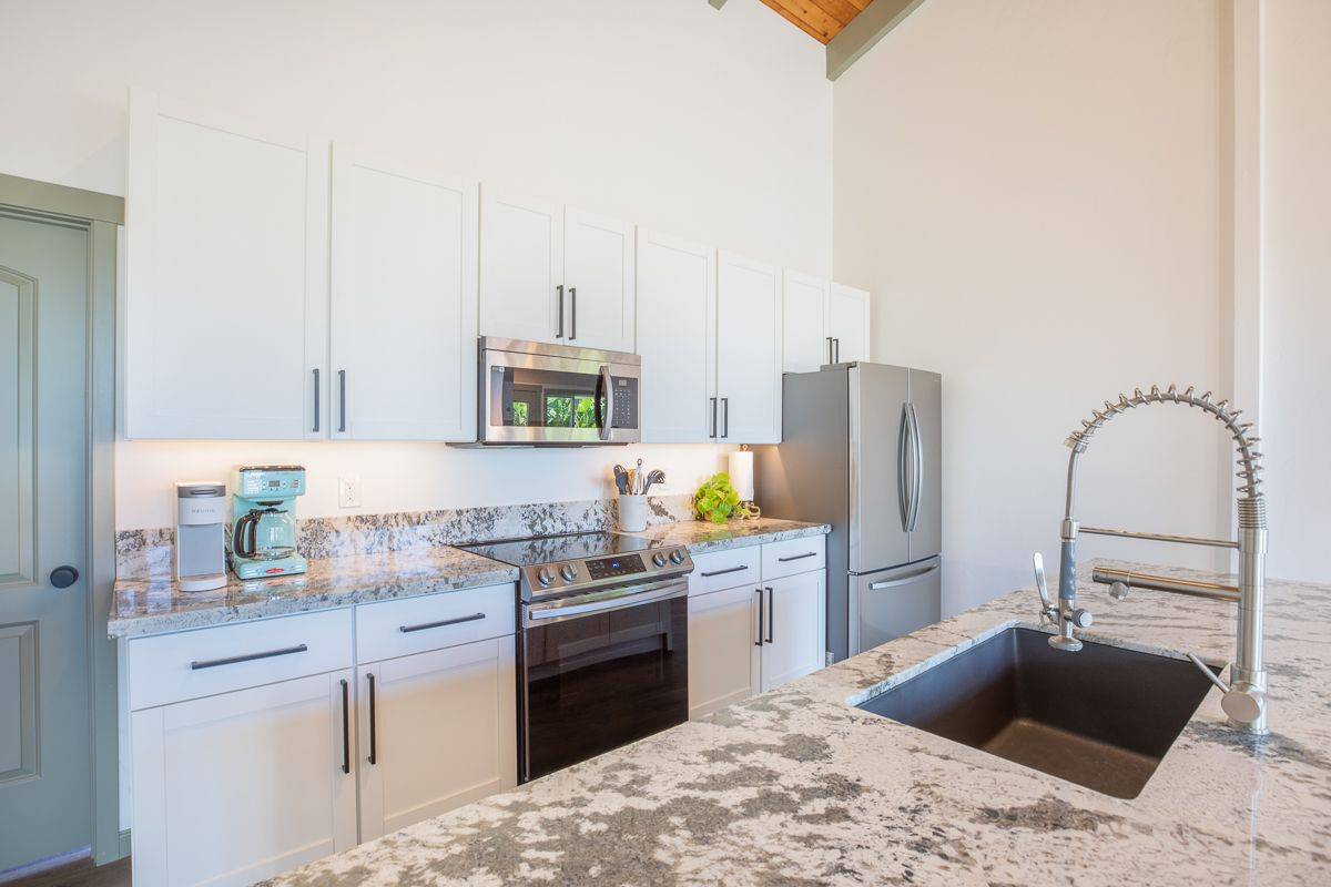 68-1788 Auhili Loop Waikoloa, HI 96738 - Photo 17 of 29 a kitchen with stainless steel appliances kitchen island granite countertop a sink stove and refrigerator