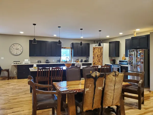 a kitchen with stainless steel appliances kitchen island granite countertop a table chairs sink and cabinets