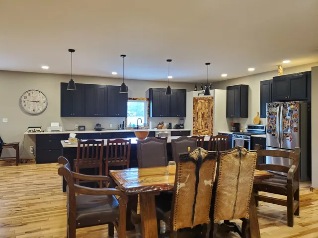 a kitchen with stainless steel appliances kitchen island granite countertop a table chairs sink and cabinets