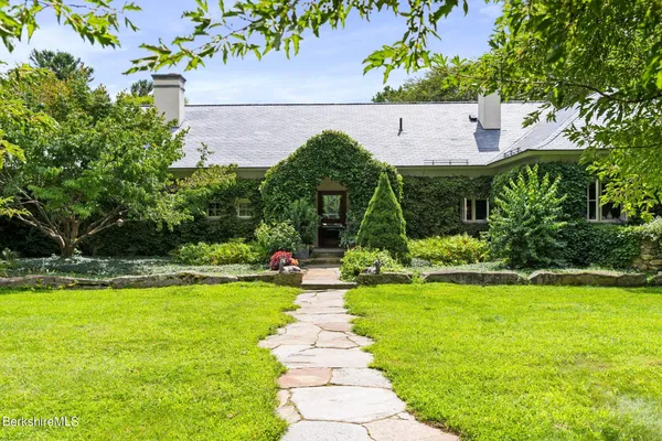 a front view of a house with swimming pool and garden