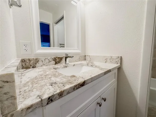 a bathroom with a granite countertop sink and a mirror