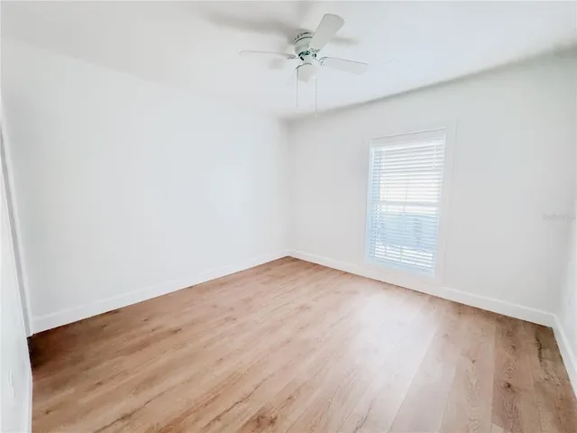 an empty room with wooden floor and ceiling fan
