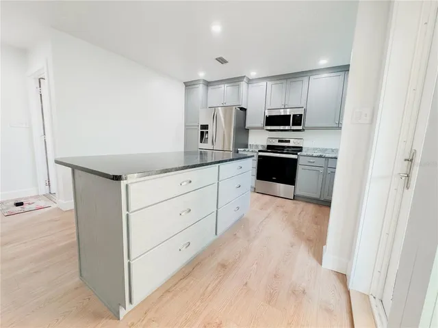 a kitchen with granite countertop white cabinets and stainless steel appliances