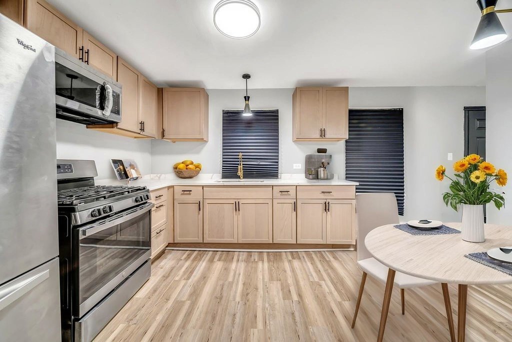 15417 Cherry Lane Markham, IL 60428 - Photo 6 of 24 a kitchen with stainless steel appliances granite countertop a stove a sink dishwasher and white cabinets with wooden floor