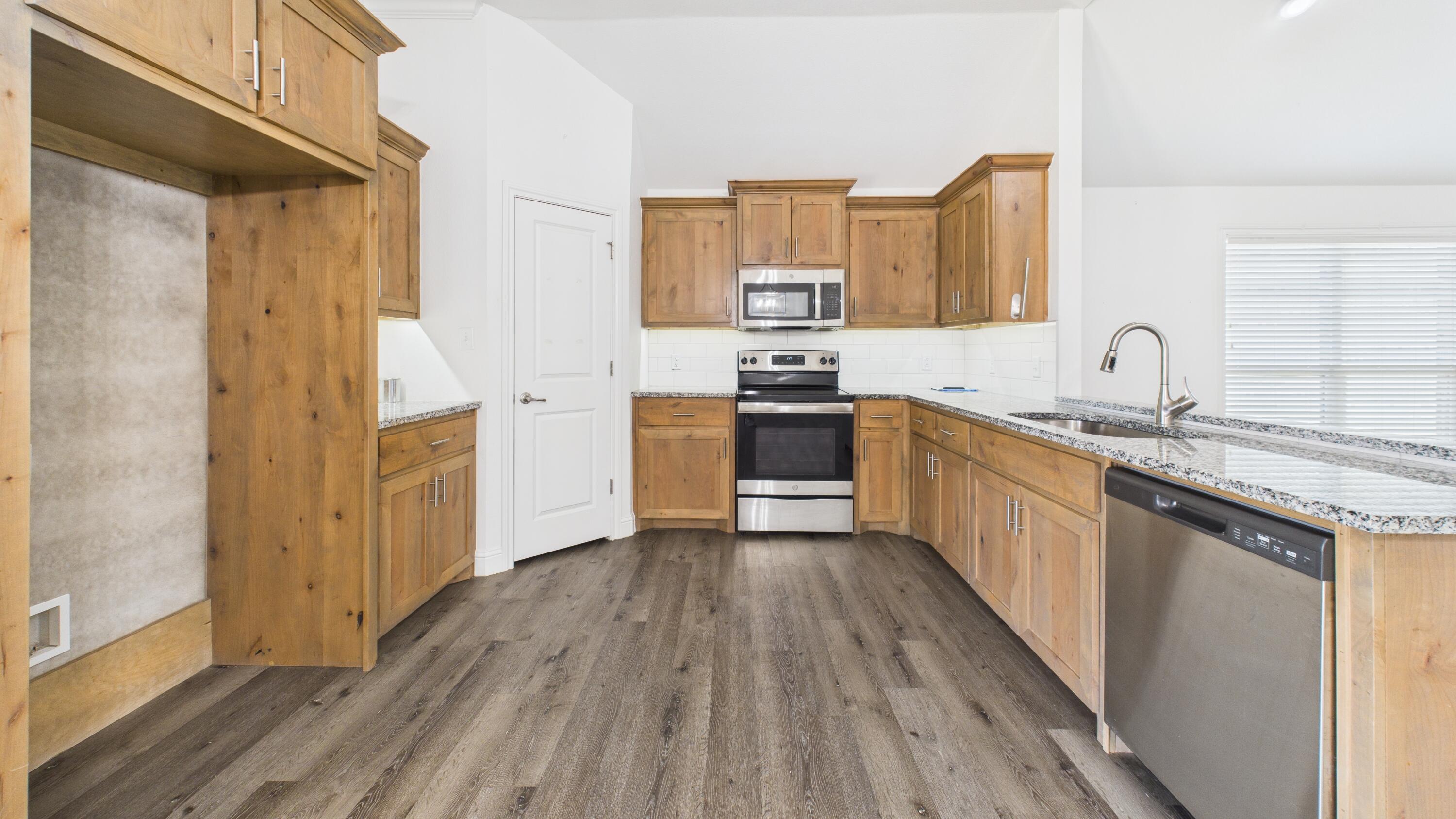 7107 23rd Street Lubbock, TX 79407 - Photo 18 of 49 a kitchen with stainless steel appliances granite countertop a sink and wooden cabinets