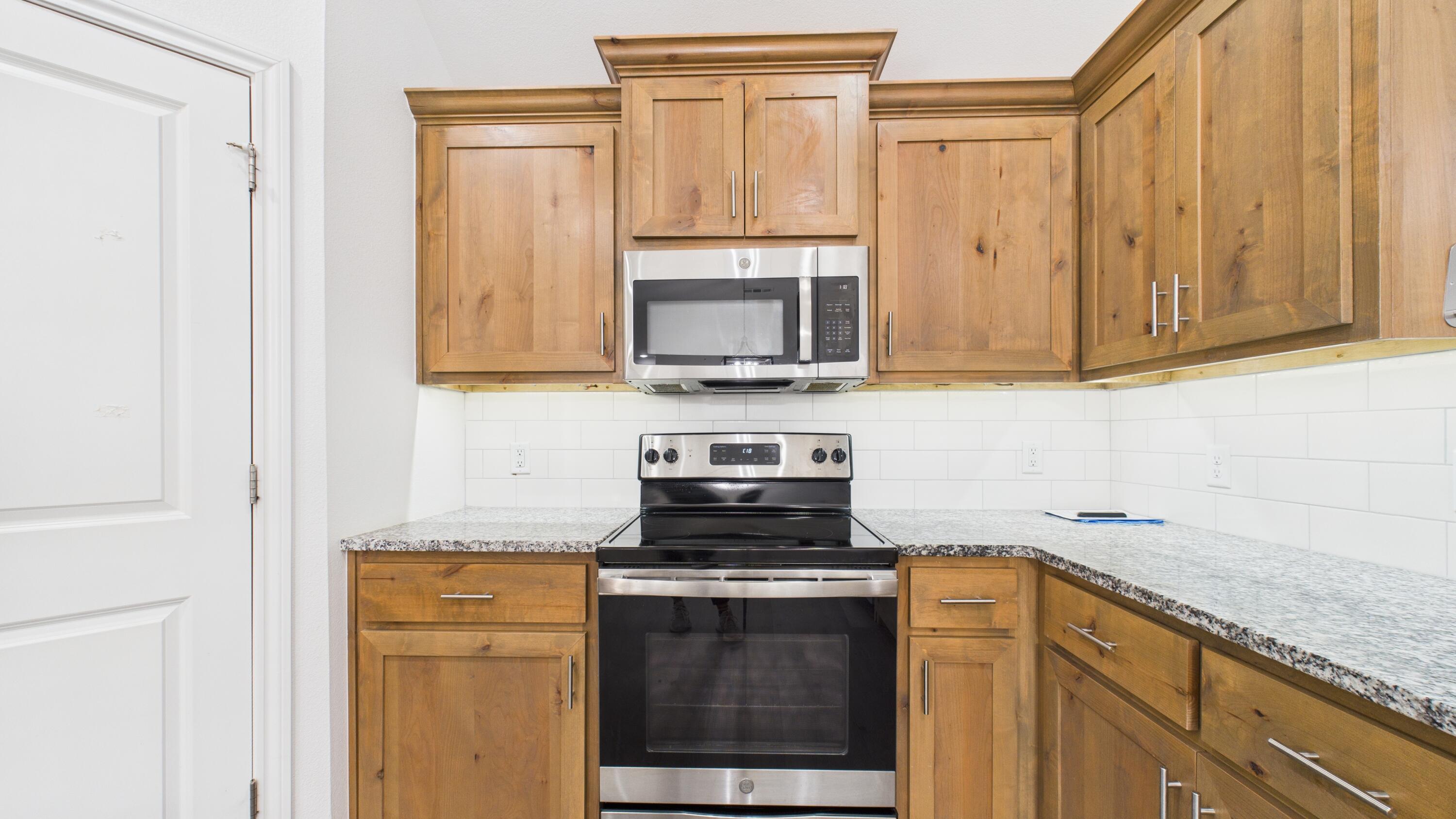 7107 23rd Street Lubbock, TX 79407 - Photo 20 of 49 a kitchen with granite countertop a stove a sink and a microwave