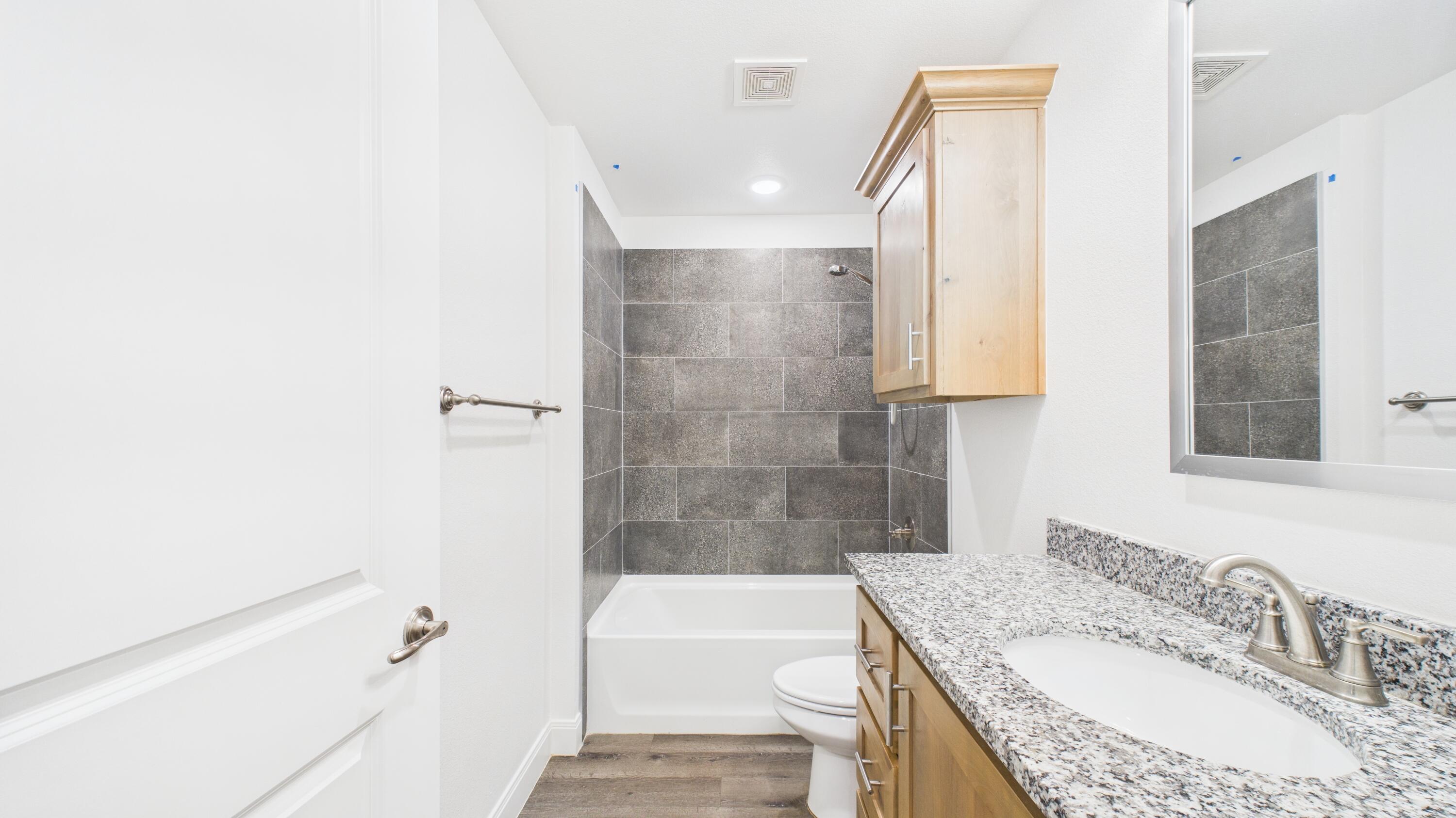 7107 23rd Street Lubbock, TX 79407 - Photo 28 of 49 a bathroom with a granite countertop bathtub a sink and a shower