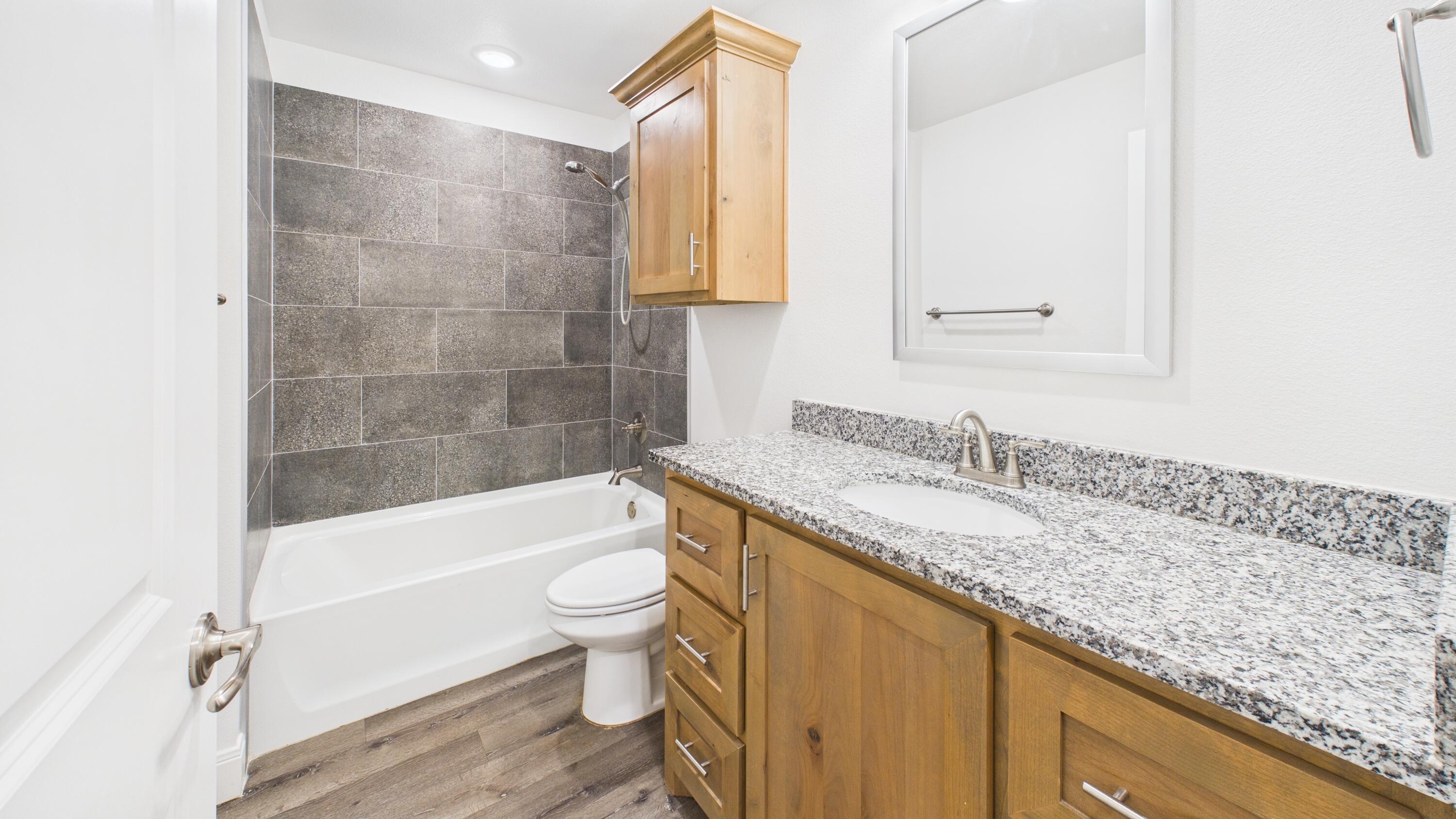 7107 23rd Street Lubbock, TX 79407 - Photo 29 of 49 a bathroom with a granite countertop sink a toilet and bathtub