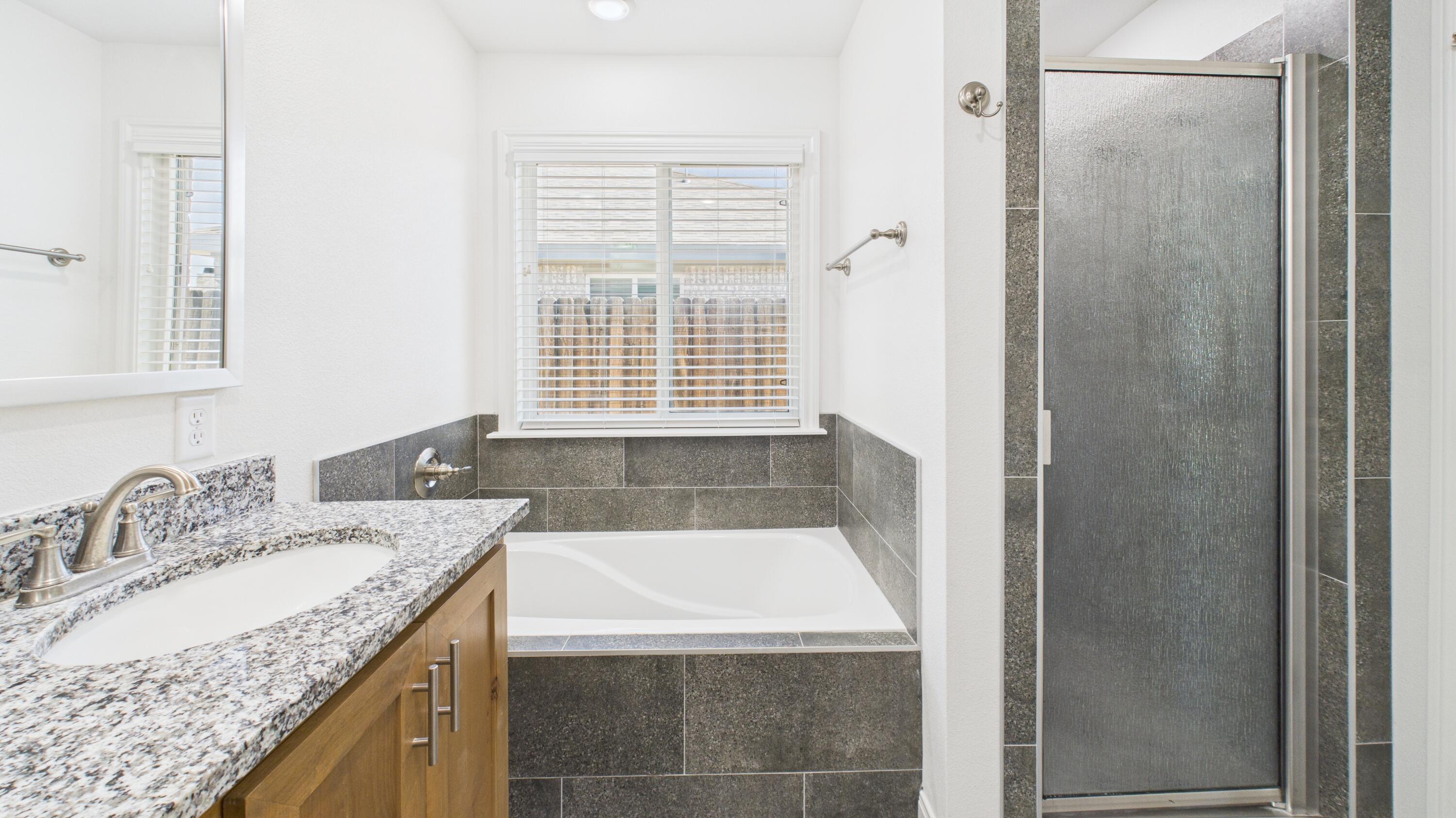 7107 23rd Street Lubbock, TX 79407 - Photo 43 of 49 a bathroom with a granite countertop sink and a bathtub