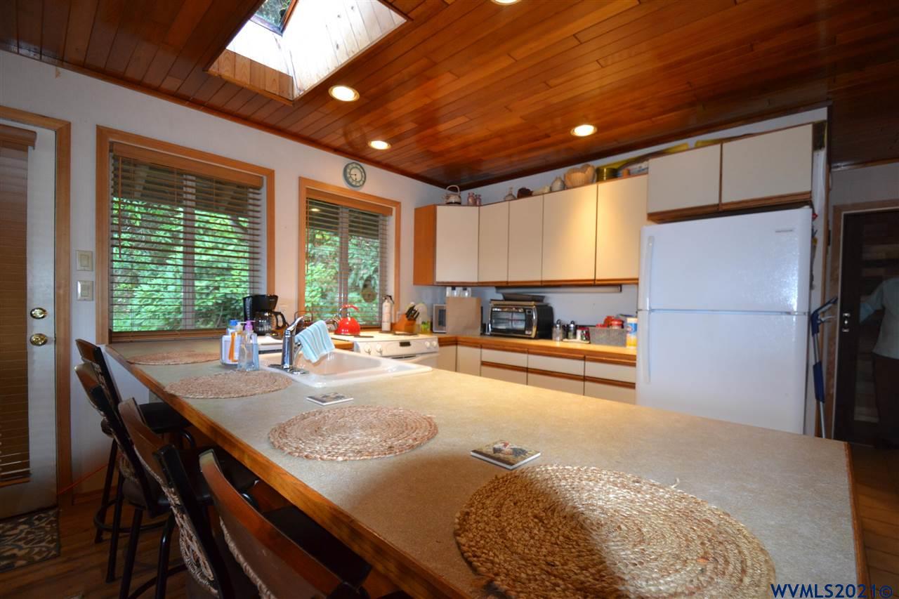 1690 Bayocean Road Northwest Tillamook, OR 97141 - Photo 10 of 25 a view of a kitchen with kitchen island a large window and a refrigerator