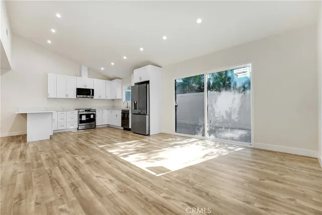 a kitchen with stainless steel appliances granite countertop a stove top oven a sink and a refrigerator