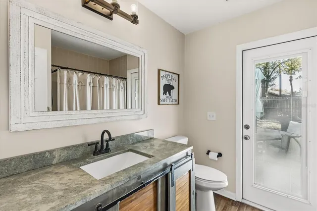 a bathroom with a granite countertop sink a toilet and a shower