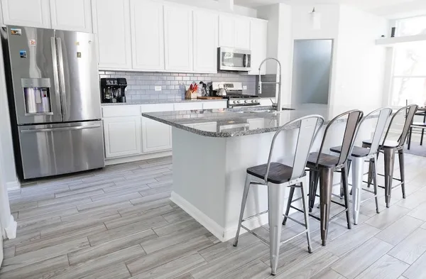 a kitchen with granite countertop stainless steel appliances a refrigerator and a stove top oven