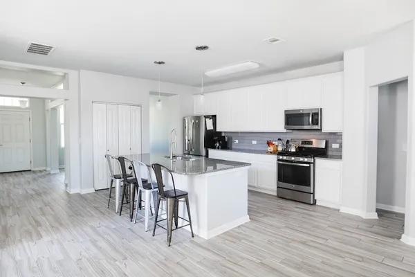 a kitchen with stainless steel appliances kitchen island granite countertop a stove top oven a sink a dining table and chairs with wooden floor
