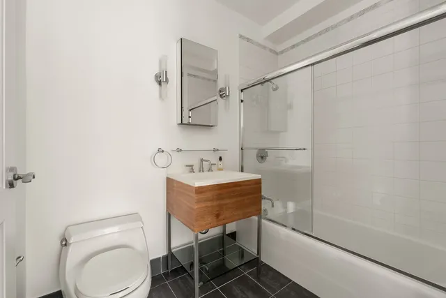 a bathroom with a granite countertop sink toilet a mirror and shower