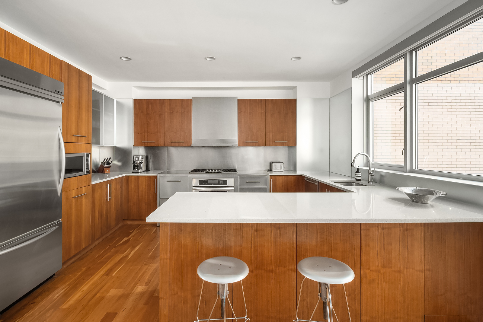 426 West 58th Street, Unit PH3 Manhattan, NY 10019 - Photo 6 of 22 a kitchen with stainless steel appliances granite countertop a sink a stove a refrigerator with white cabinets and wooden floor