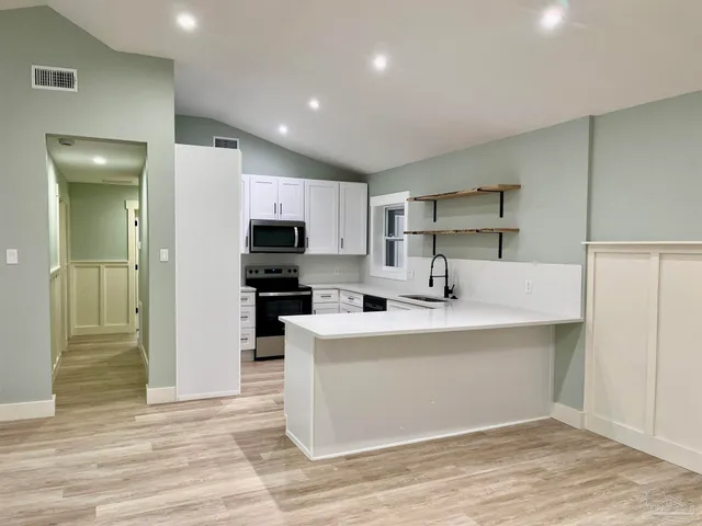 a view of kitchen with stainless steel appliances refrigerator sink and cabinets
