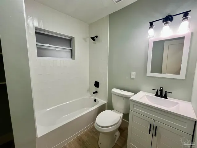 an empty room with wooden floor ceiling fan and windows