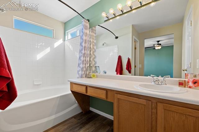 7655 Coffee Road Peyton, CO 80831 - Photo 15 of 31 Bathroom featuring shower / bathtub combination with curtain, vanity, ceiling fan, and wood-type flooring