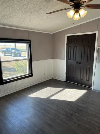 an empty room with wooden floor cabinet and windows