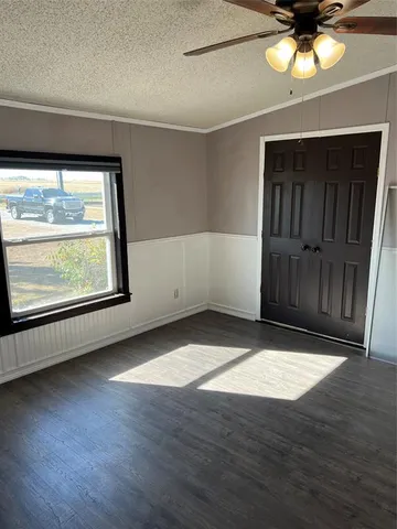 an empty room with wooden floor cabinet and windows