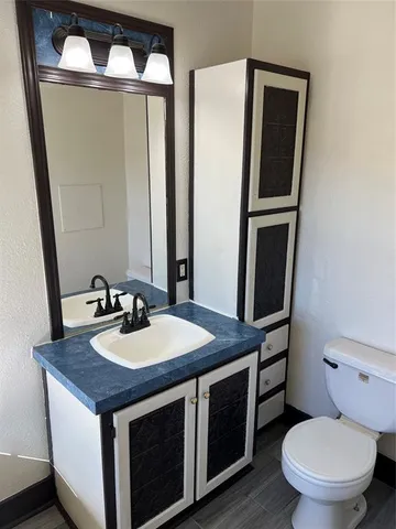 a bathroom with a granite countertop toilet sink and mirror