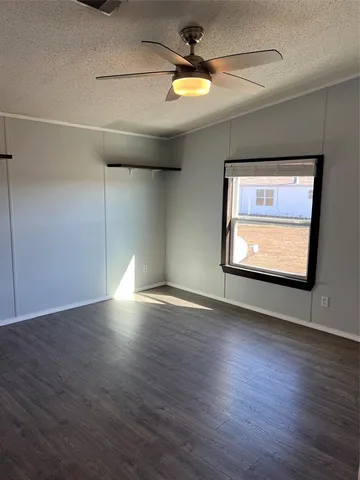 a view of empty room with wooden floor and fan