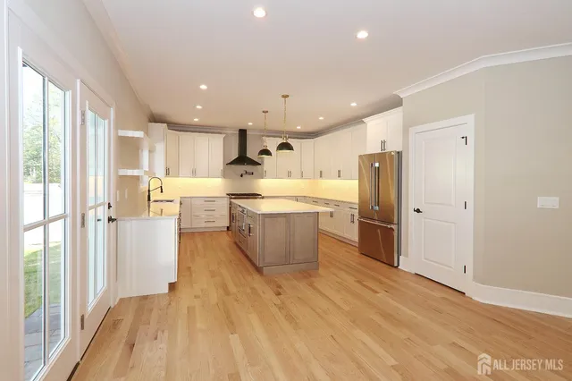 a large kitchen with a large counter top a sink stainless steel appliances and cabinets