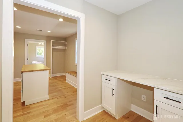 a view of a hallway with wooden floor and cabinet