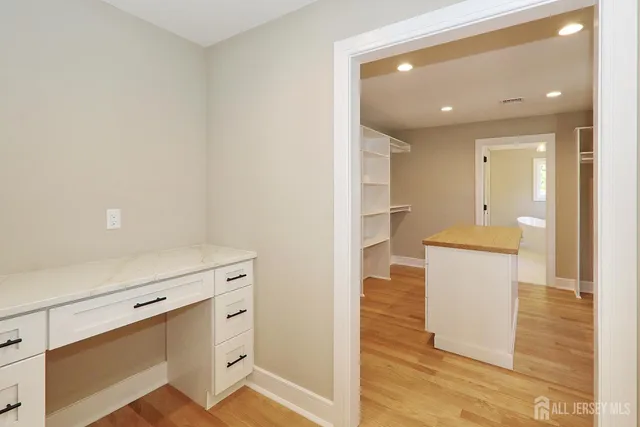 a hallway with white cabinets and wooden floor